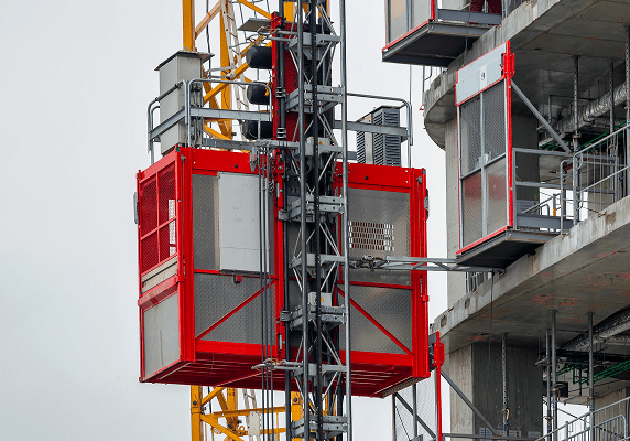 Red construction elevator beside unfinished building